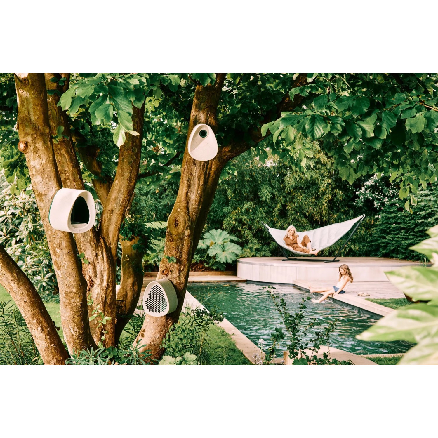 Mehrere graue Elho Vogelhäuser Essential an einem Baum im Garten.