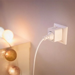 Philips Smart Steckdose Typ F weiß, in Wandsteckdose gesteckt. Misst Energieverbrauch, macht Geräte smart. Lichterkette im Hintergrund.