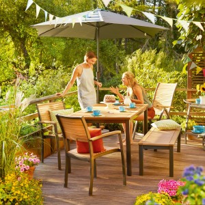 Szene mit Bonlee Gartenbank (2-Sitzer) aus FSC®-Eukalyptusholz mit Tisch und Personen auf einer Terrasse.