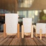Drei Näve LED-Tischleuchten Madita aus Leinen und Holz in Natur auf einem Tisch.
