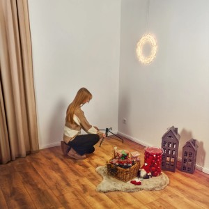 Frau montiert Kunsttanne Blavand (90cm) mit Deko im Wohnzimmer. Künstlicher Weihnachtsbaum mit Metallständer.