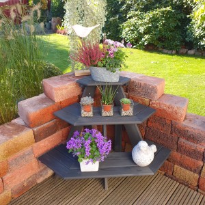 Anthrazitfarbene Blumentreppe Anja Eckelement mit Pflanzen und Deko im Garten.