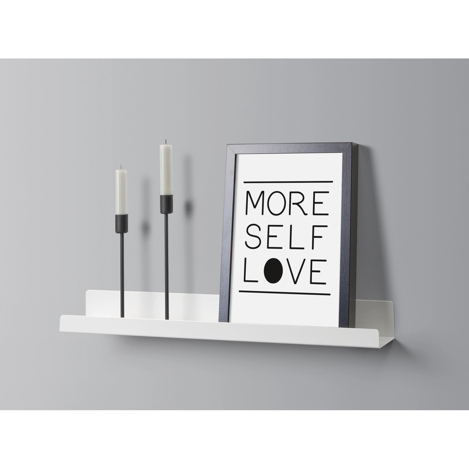 Weißes Metall-Wandregal Bix 80 cm mit Deko-Elementen wie Kerzen und Bilderrahmen.