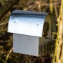 Elfenbeinfarbener Nistkasten „Rundhaus“ mit Alu-Dach, hängend an einem Baum.