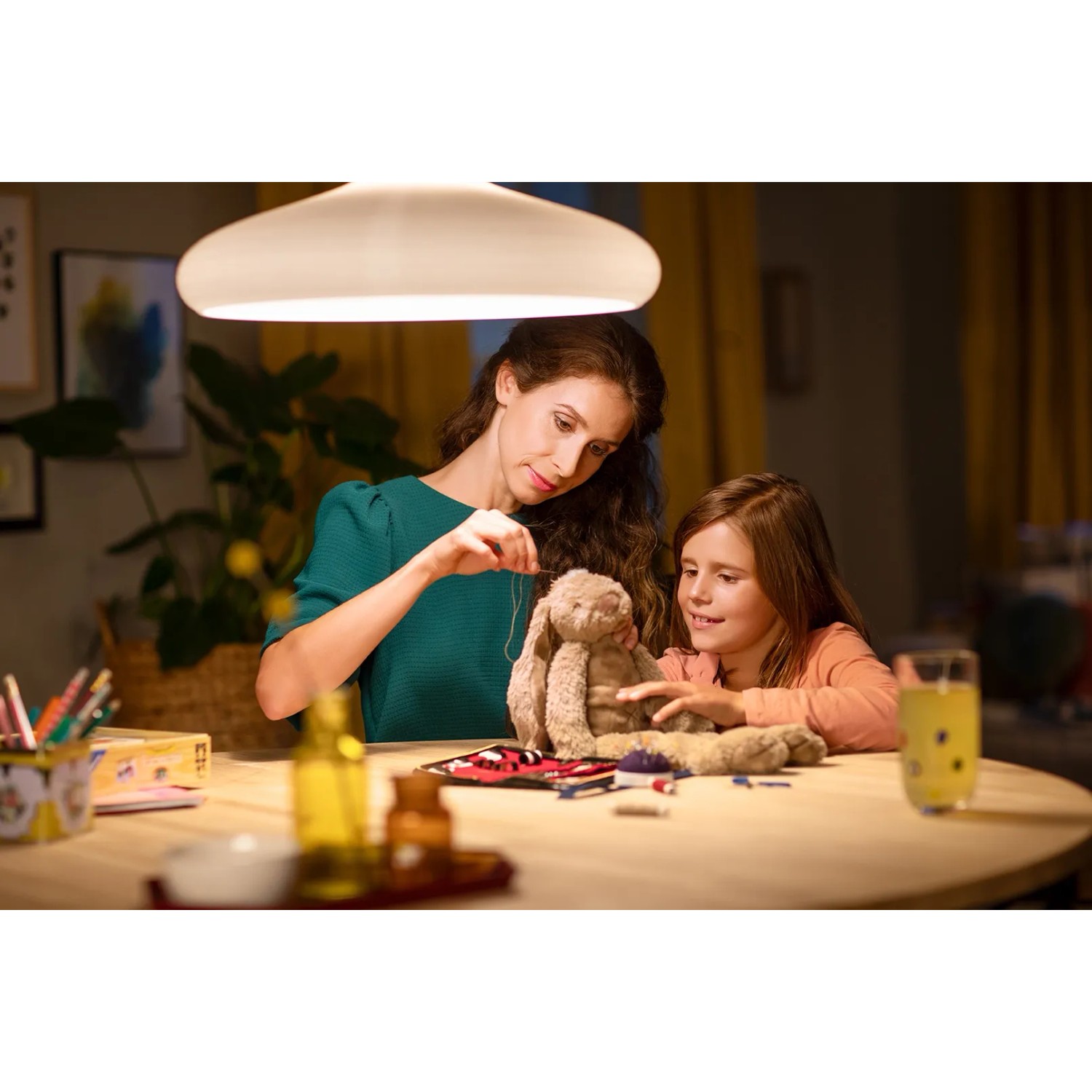 Szene mit Philips E14 LED Reflektorlampe über Tisch, Mutter und Tochter beim Nähen eines Stofftiers.
