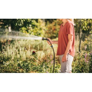 Frau gießt Pflanzen mit Fiskars Sprühpistole mit 3 Funktionen im Garten.