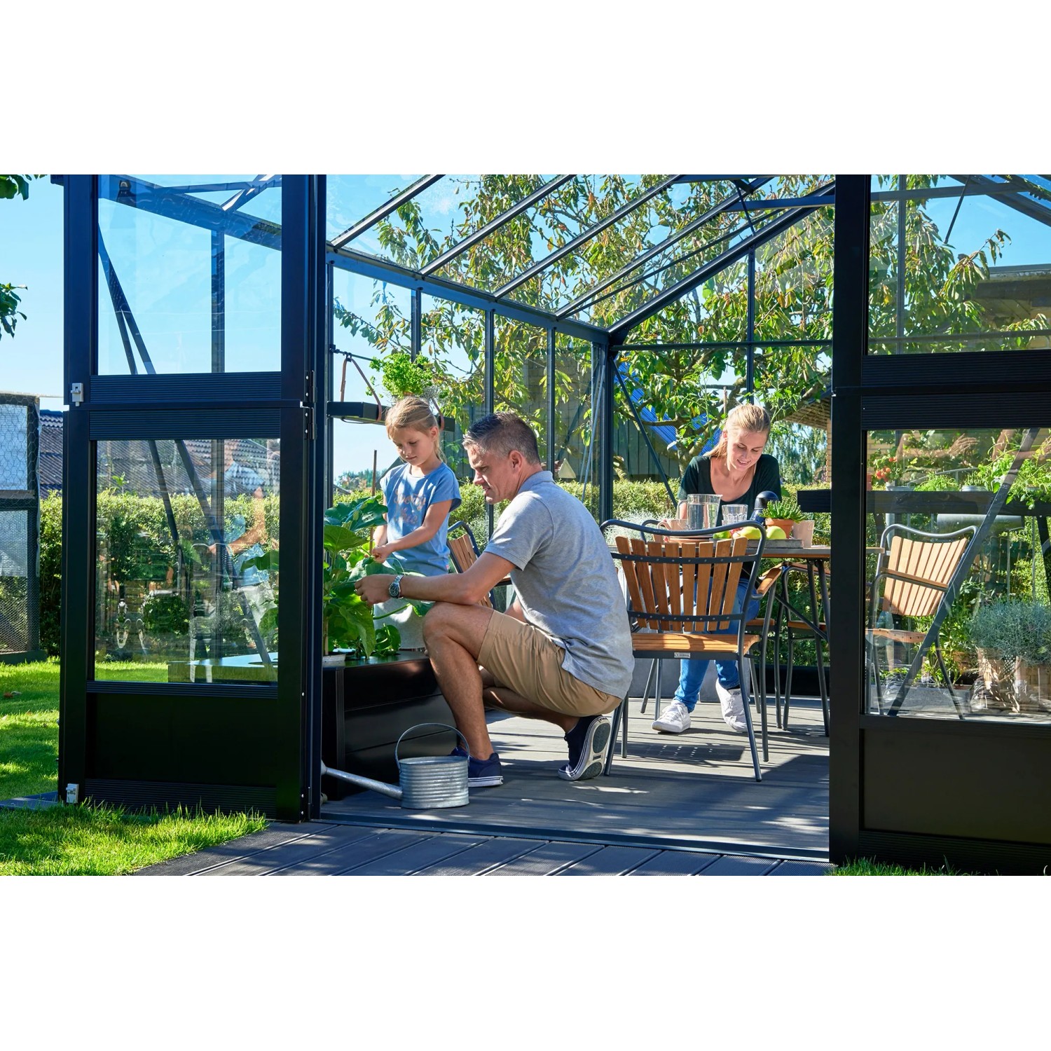 Familie im Juliana Gewächshaus Premium 13 Anthrazit. Das Gewächshaus bietet Platz zum Gärtnern und Entspannen.