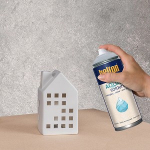 Hand sprüht Belton Free AQUAcolours Klarlack seidenglänzend 400 ml auf weißes Deko-Haus. Wasserbasierender Klarlack-Spray.