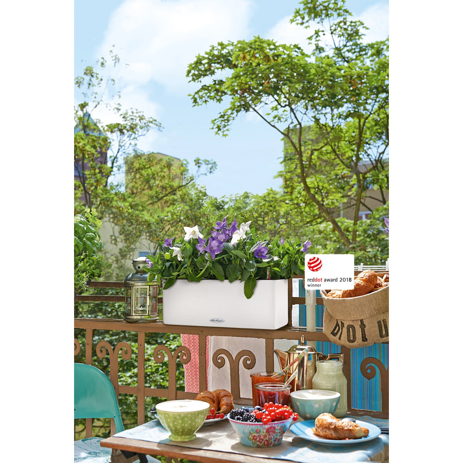 Lechuza Cube Color Triple Pflanzgefäß, 40cm, weiß, mit lila und weißen Blumen auf einem Balkon.