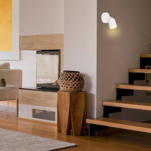 Weiße Brilo Wandleuchte Tabo, 1-flammig, schwenkbar, GU10 Fassung, montiert an einer Wand neben einer Treppe.