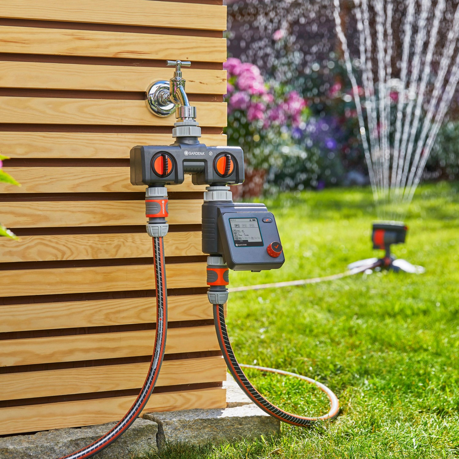 Gardena Bewässerungscomputer Select am Wasserhahn mit Regner im Garten.