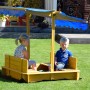 Dobar Sandkasten mit Dach, Kinder spielen im gelben Holzsandkasten mit blauem Sonnenschutz.