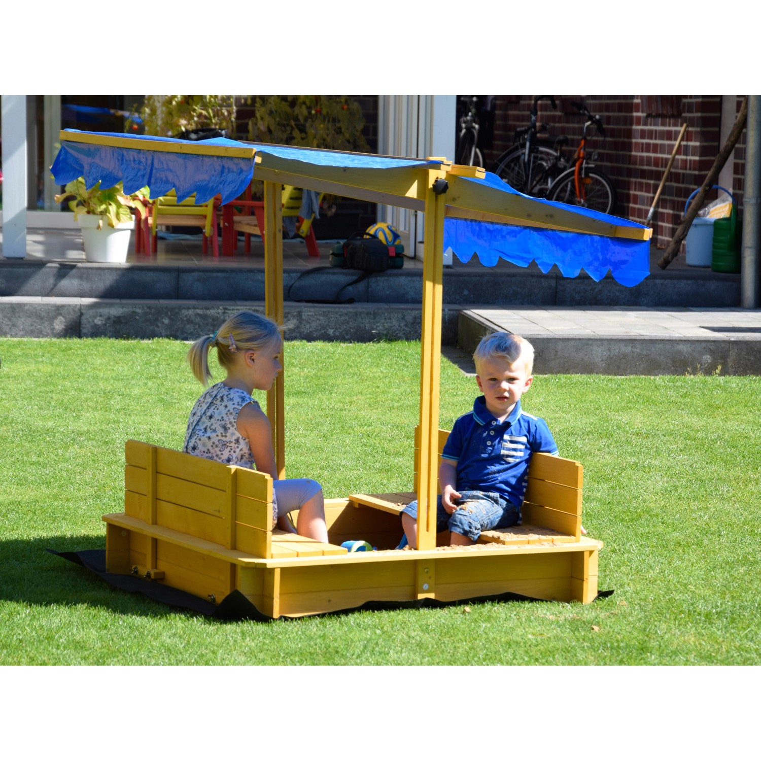 Dobar Sandkasten mit Dach, Kinder spielen im gelben Holzsandkasten mit blauem Sonnenschutz.