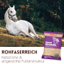 Weißes Pferd liegt auf Wiese. Lila Beutel Supravit Luzernecobs Pferdefutter 20 kg, rohfaserreich.
