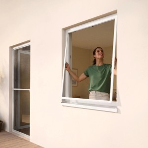 Frau montiert tesa® Insect Stop Fliegengitter mit Alurahmen in ein Fenster.