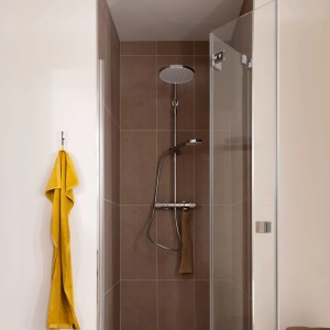 Schöner Wohnen Duschsystem Glaia mit Thermostat, chromfarben, in Dusche mit braunen Fliesen.