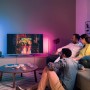 Wohnzimmer mit Philips Hue Gradient Signe Tischleuchte in Weiß, die farbiges Licht ausstrahlt.