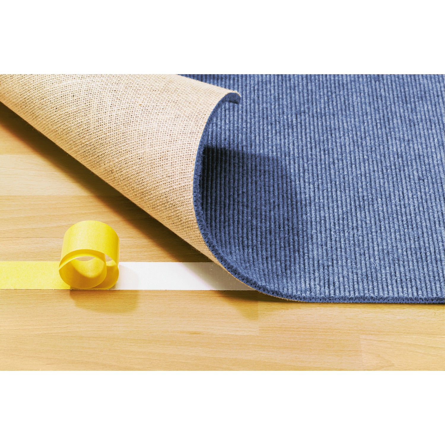LUX doppelseitiges Klebeband fixiert Teppich auf Holzboden. Rolle sichtbar.