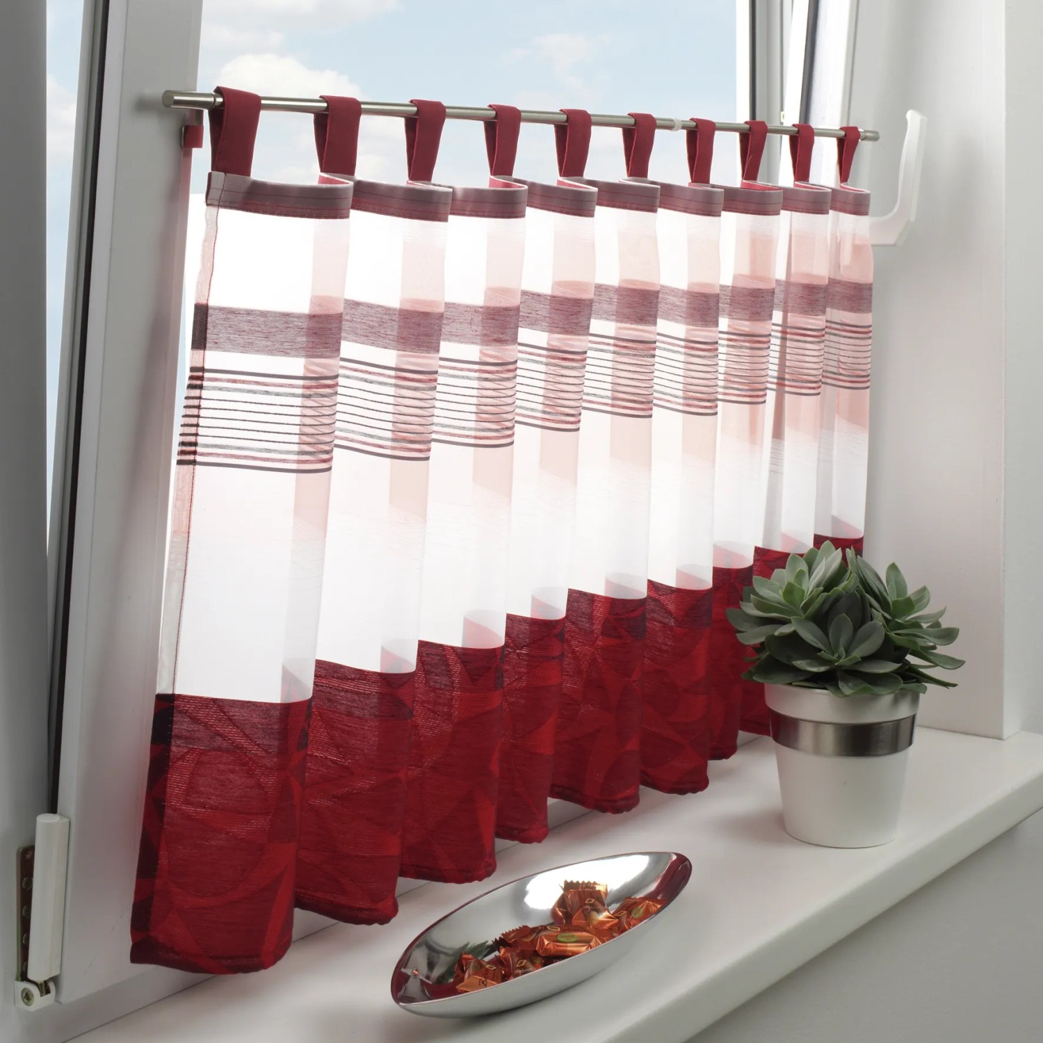 Gardinia Klemmstange Press&Go mit rotem Kurzgardinen-Behang am Fenster.