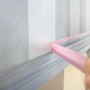Anwendung von Tesa Malerband Professional Sensitive (rosa) auf einer gestreiften Tapete.
