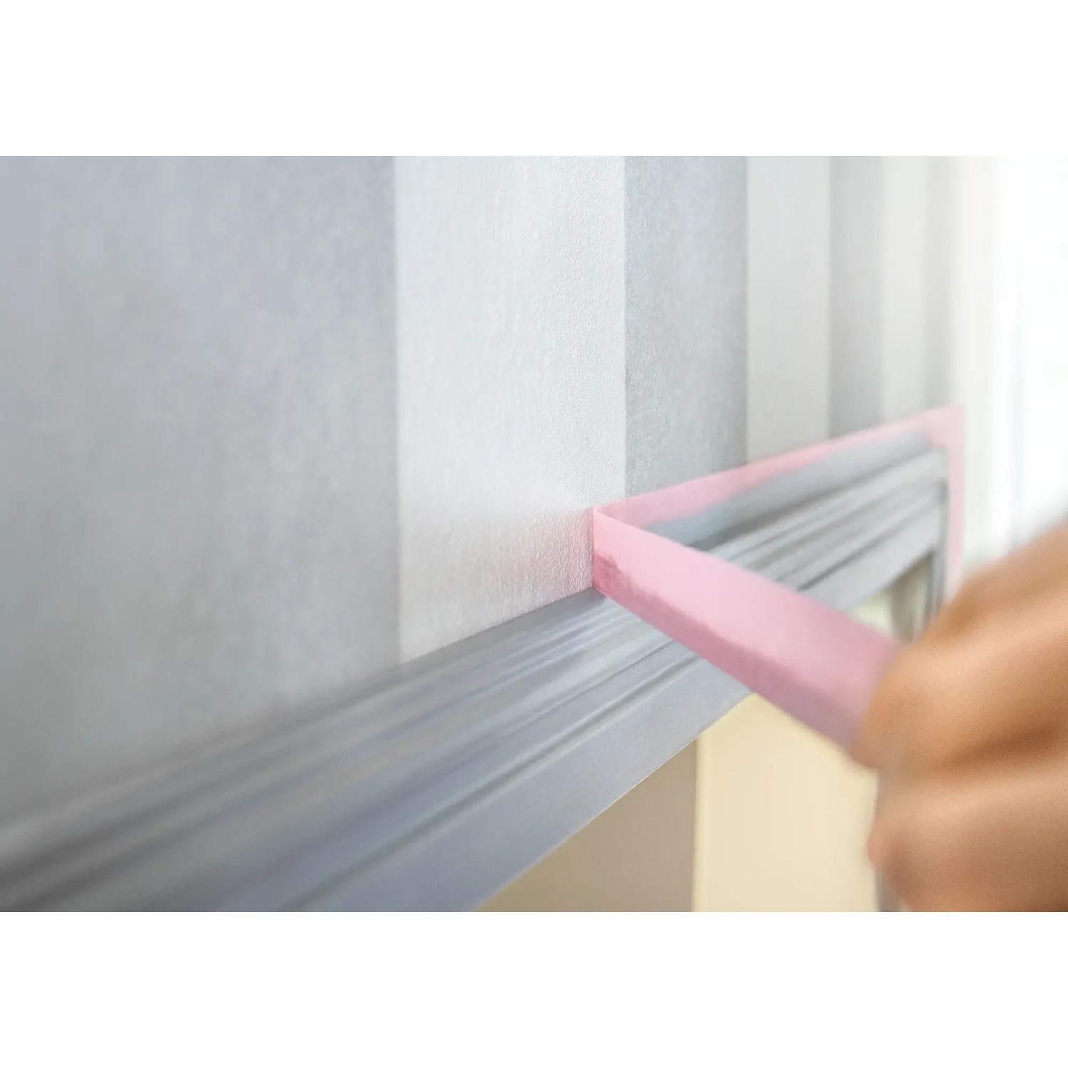Anwendung von Tesa Malerband Professional Sensitive (rosa) auf einer gestreiften Tapete.