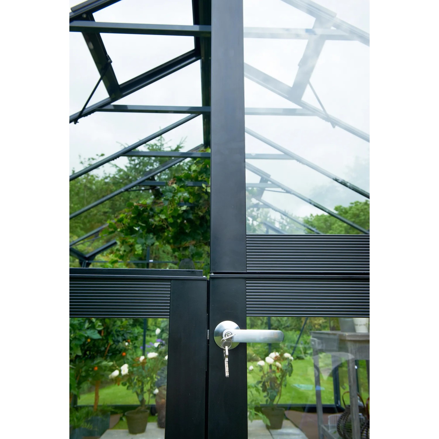 Detailaufnahme: Juliana Premium 8 Gewächshaus in Anthrazit, Tür mit Griff und Schlüssel, Pflanzen im Inneren.