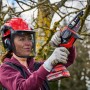Frau mit Astkettensäge beim Baumschnitt. Einhell Kettenöl-Spray für Motorsägen-Zubehör.