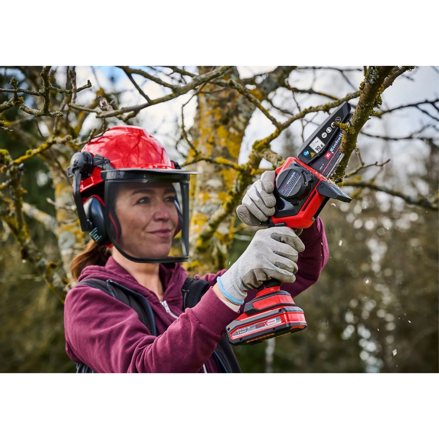 Frau mit Astkettensäge beim Baumschnitt. Einhell Kettenöl-Spray für Motorsägen-Zubehör.