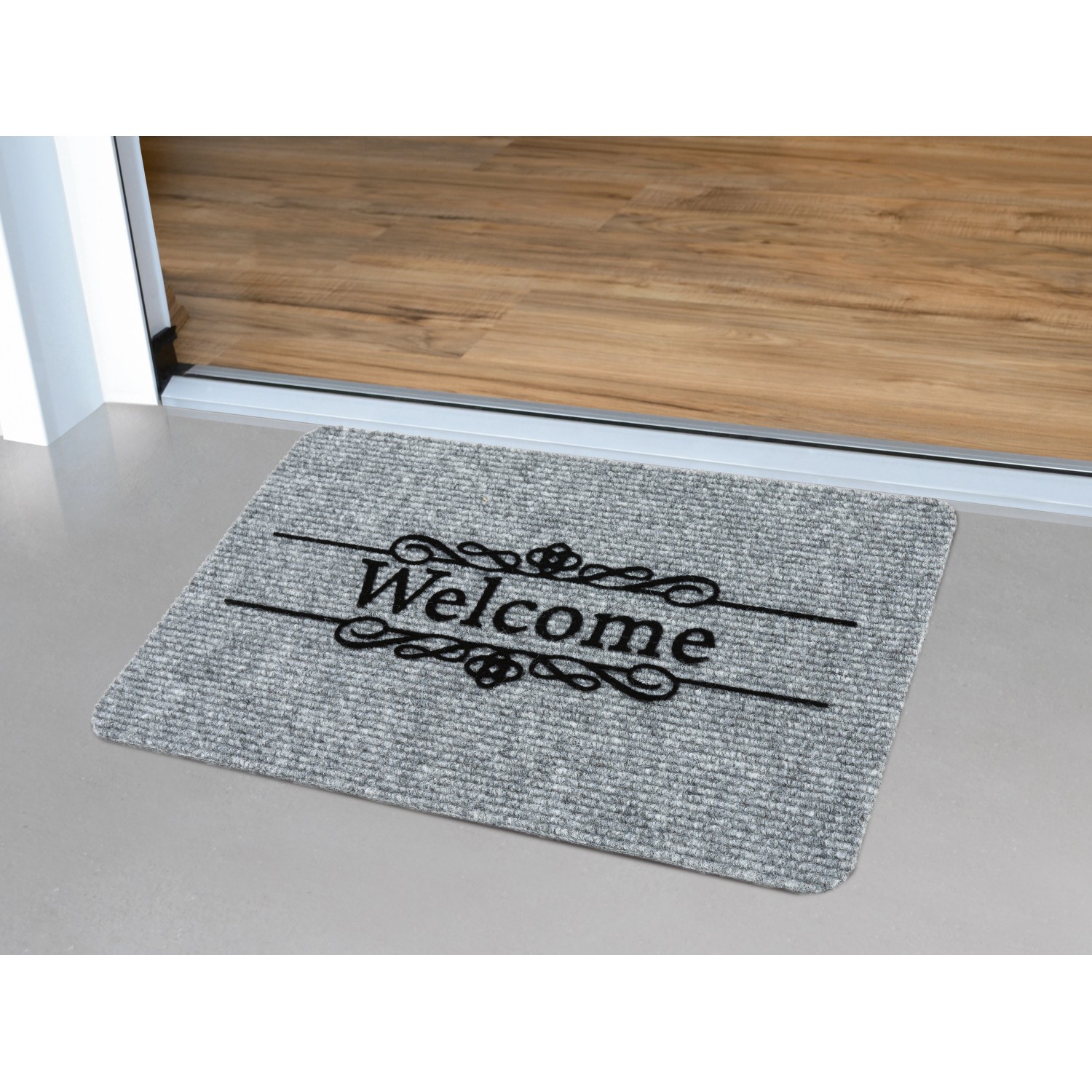 Graue Ripsmatte „Welcome“ 40x60 cm vor einer Tür. Fußmatte für den Innenbereich mit Schriftzug.