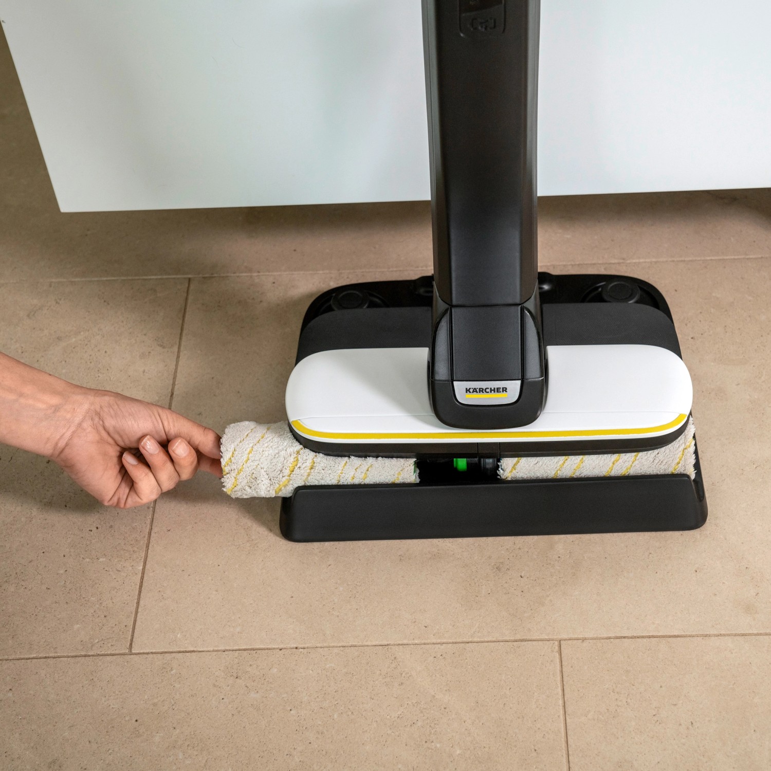 Kärcher Akku-Hartbodenreiniger FC 4-4 in Weiß-Schwarz mit Hand an der rotierenden Walze.