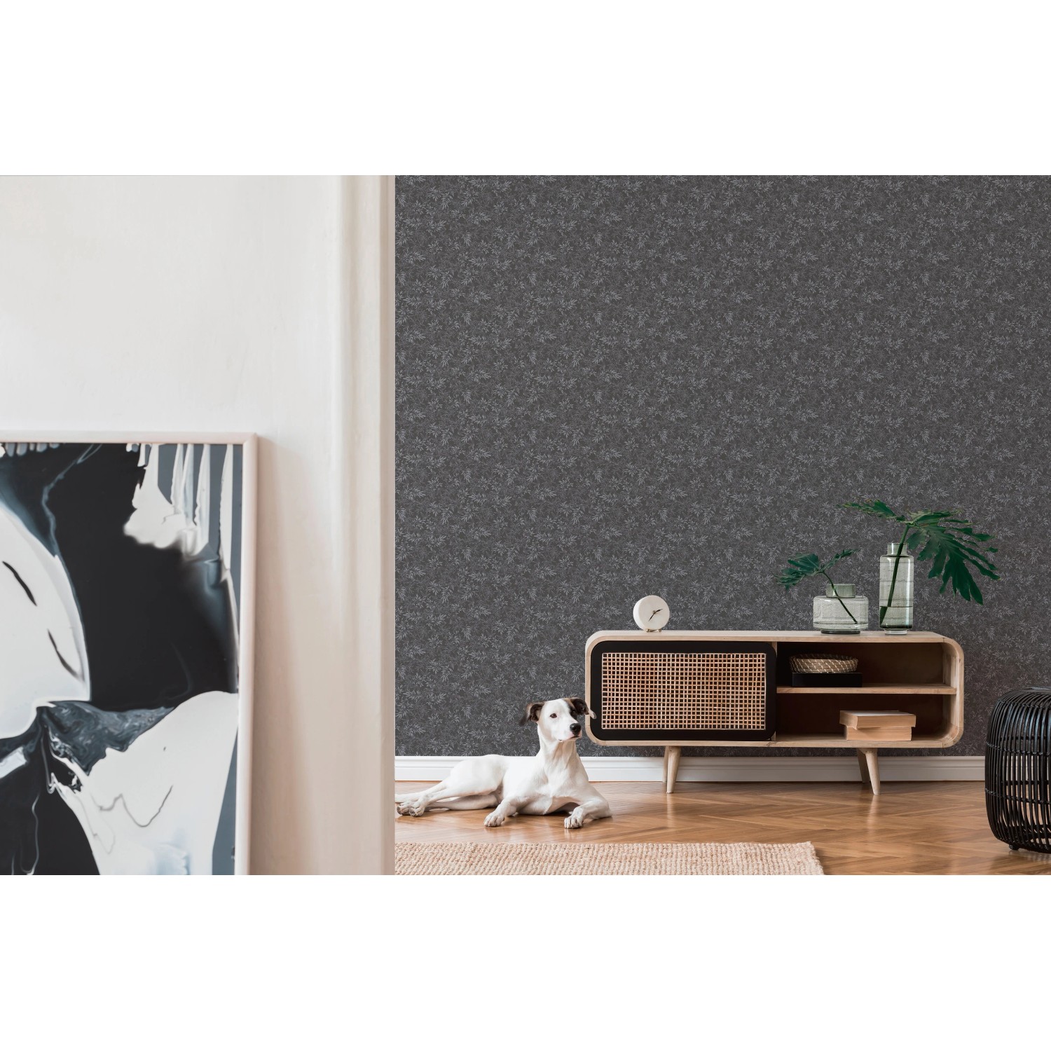 A.S. Création Vliestapete Blätter, schwarz-grau, im Wohnraum mit Hund und Kommode.
