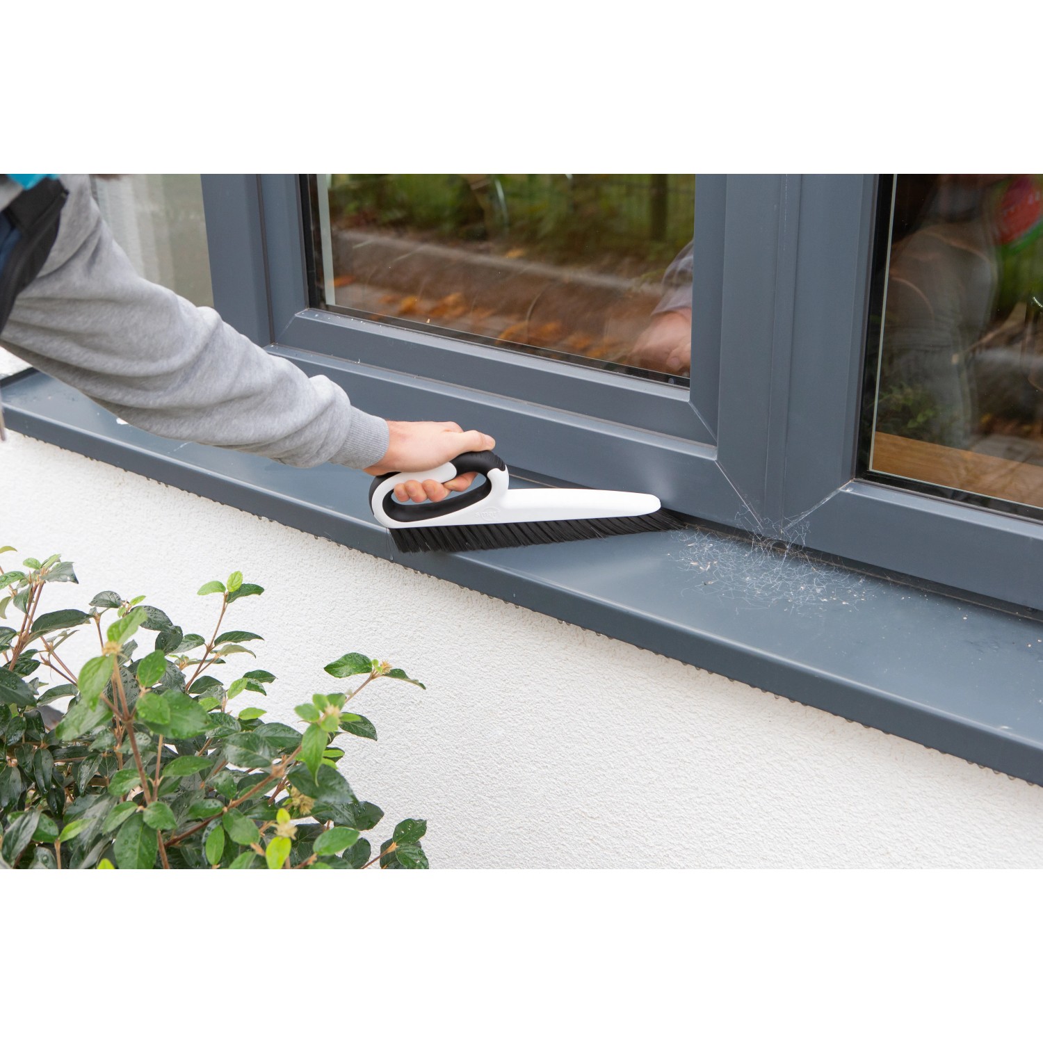SmartQ Haushalts- & Tapezierbürste im Einsatz zum Reinigen eines Fensterrahmens.