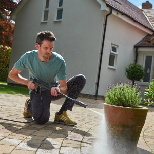 Mann reinigt Pflanzkübel mit Bosch Hochdruckreiniger UniversalAquatak 125.
