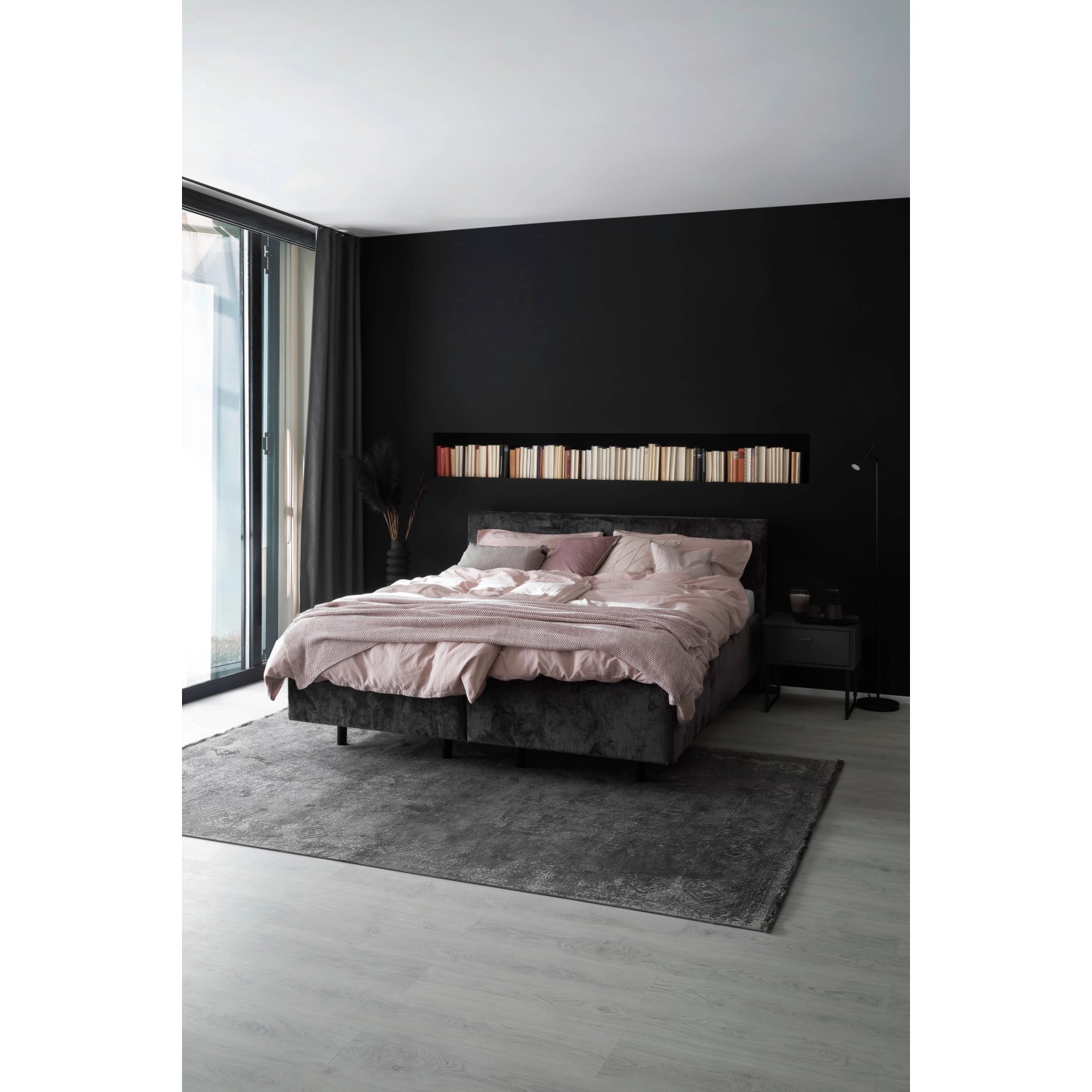 Schlafzimmer mit schwarzer Wand, Bett mit rosa Bettwäsche und grauem Teppich.