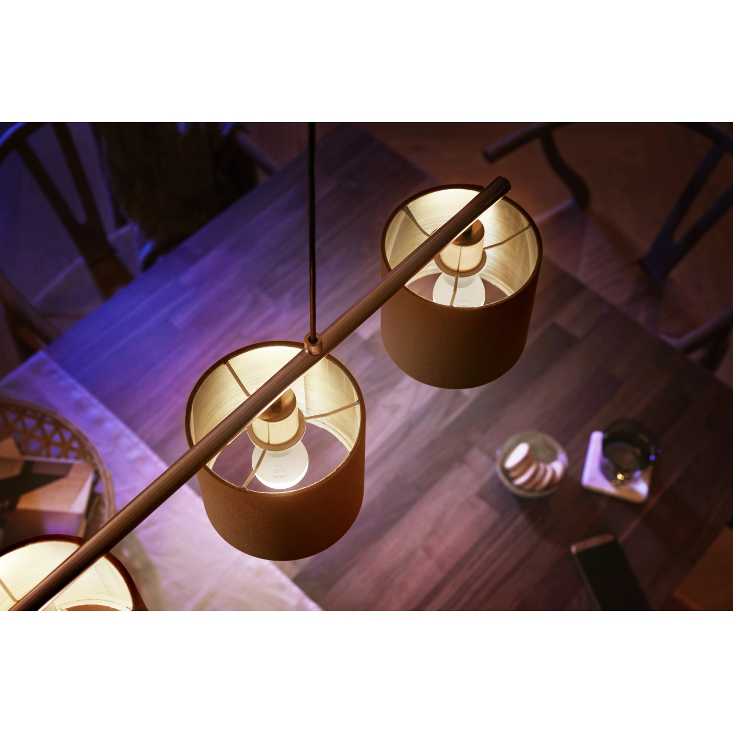 Philips Hue Luster Doppelpack E14 mit warmweißem Licht in Lampenschirmen über einem Tisch.