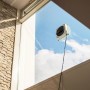 Kärcher RCW 4 Fensterputzroboter bei der Arbeit an einem Fenster mit blauem Himmel im Hintergrund.