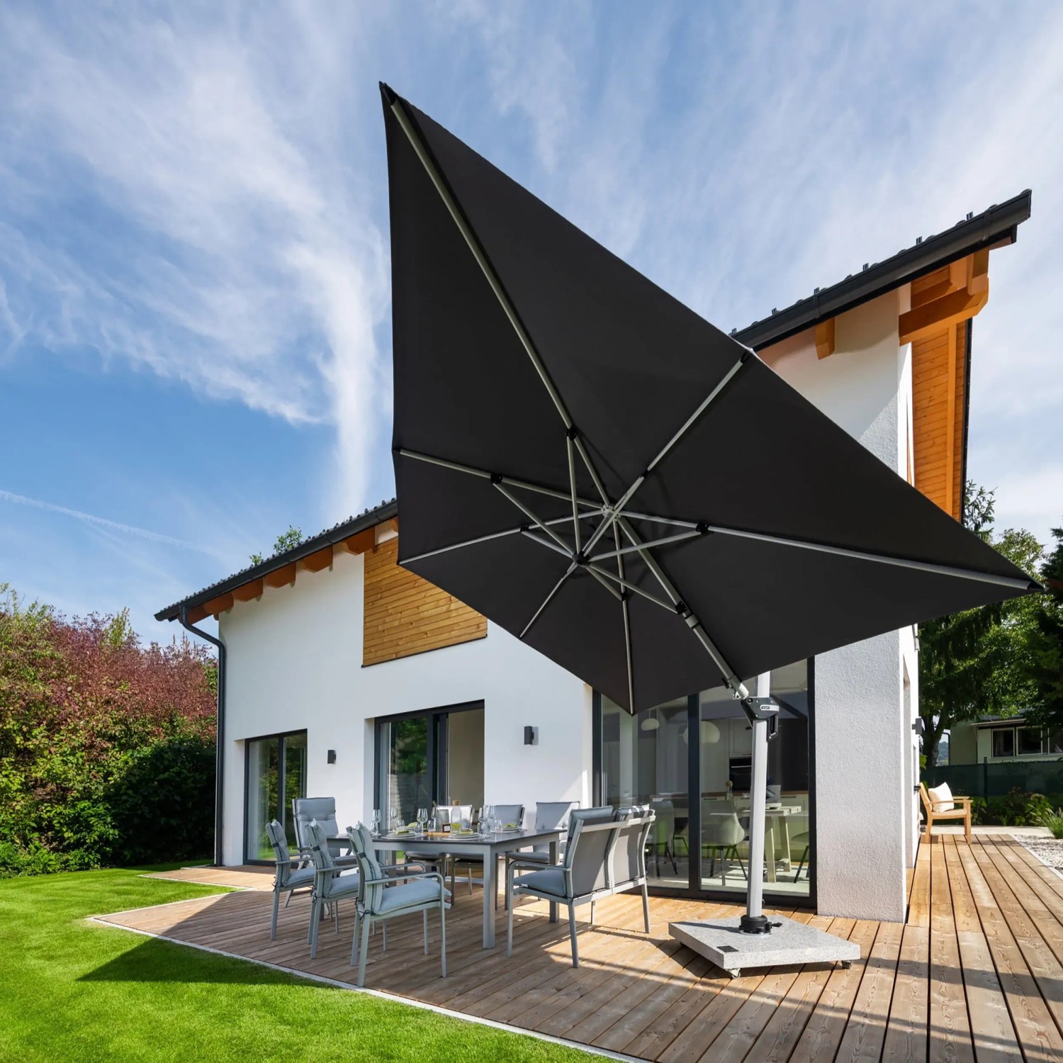 Anthrazitfarbener Doppler Ampelschirm Active II 260x350 cm mit Kurbel über einer Sitzgruppe im Garten.