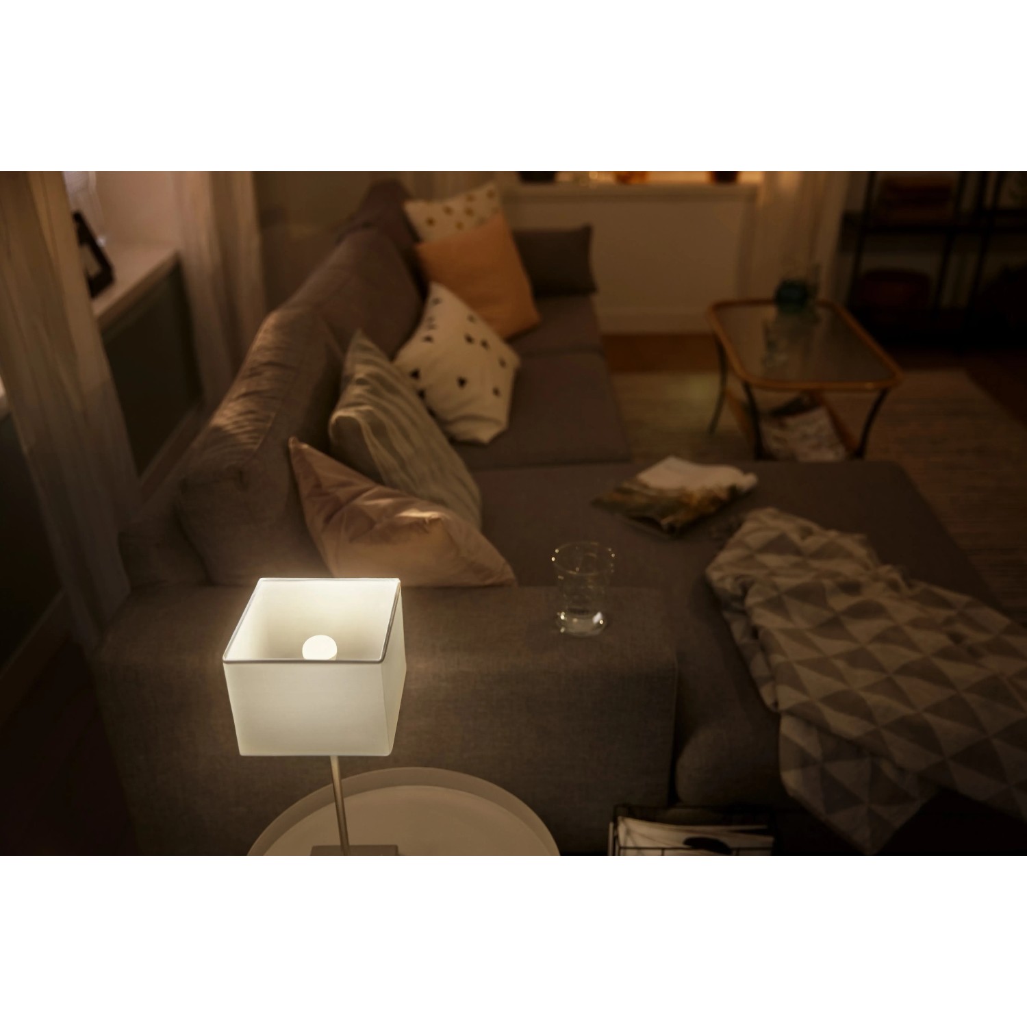 Philips Hue Luster E14 Lampe im Wohnzimmer mit warmweißem Licht.