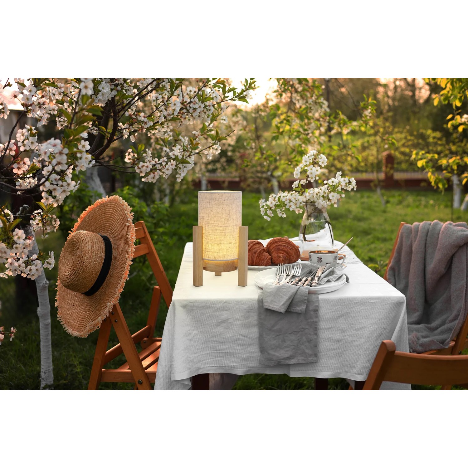 Näve LED-Tischleuchte Madita mit Leinen-Schirm und Holzfuß auf Gartentisch.