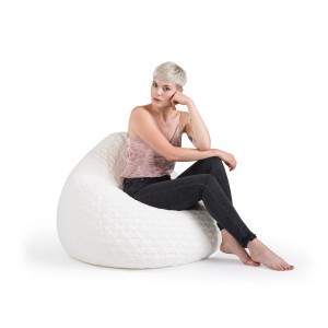 Frau sitzt entspannt im weißen Sitting Point Sitzsack BeanBag Fluffy mit Herzmuster.