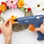 Steinel Heißklebepistole beim Anbringen von Blumen auf einem Kranz, mit transparenten Heißklebesticks.