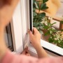Montage des weißen tesa® Insect Stop Fliegengitters am Fensterrahmen.