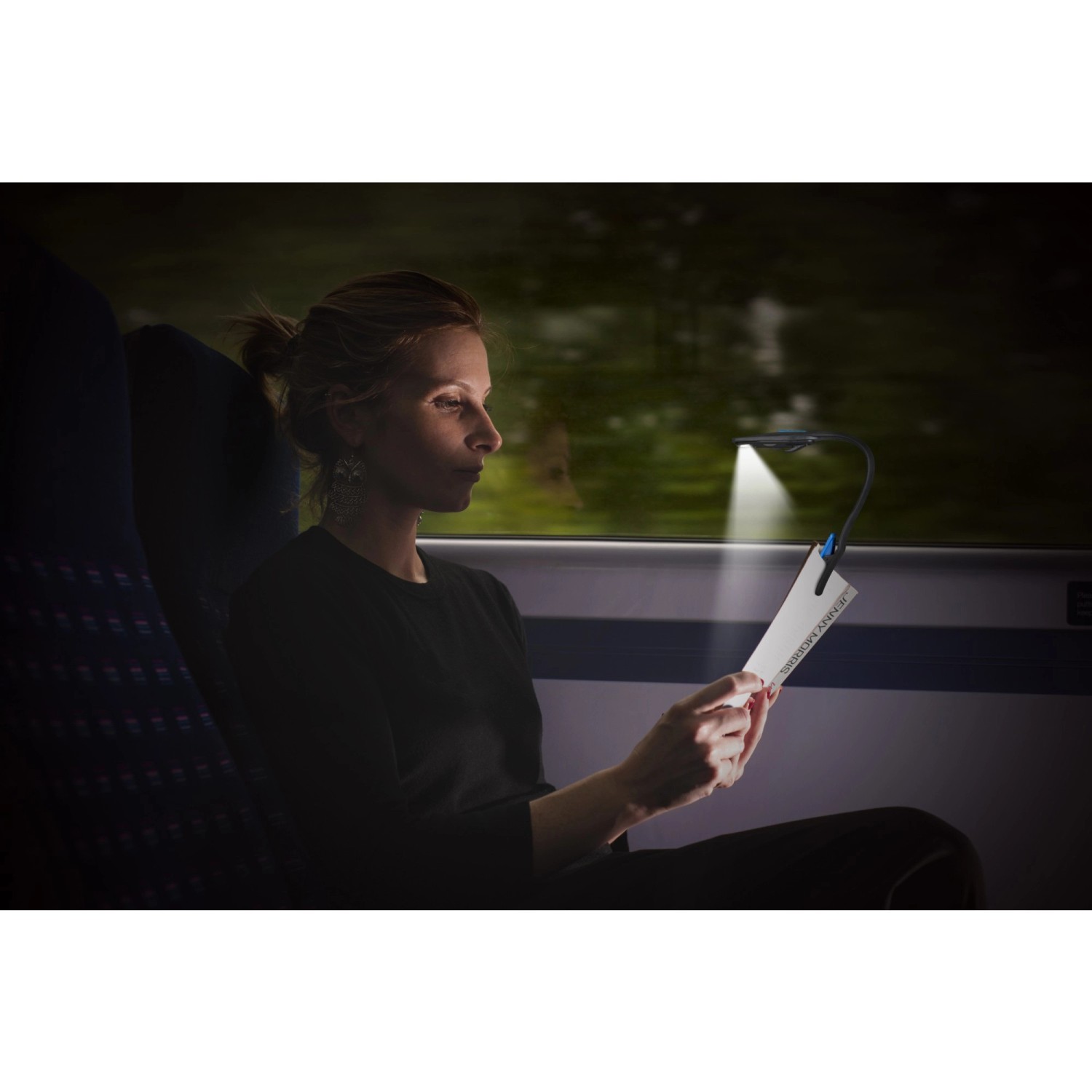 Frau liest mit Energizer Booklight Speziallampe im Zug. LED Leselampe mit flexiblem Hals.