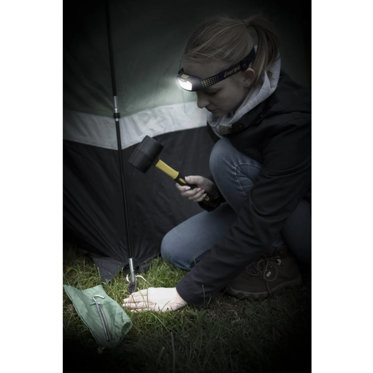 Frau beim Aufbau eines Zeltes mit Energizer Kopflampe Compact Sport Headlamp. Inkl. Batterien.