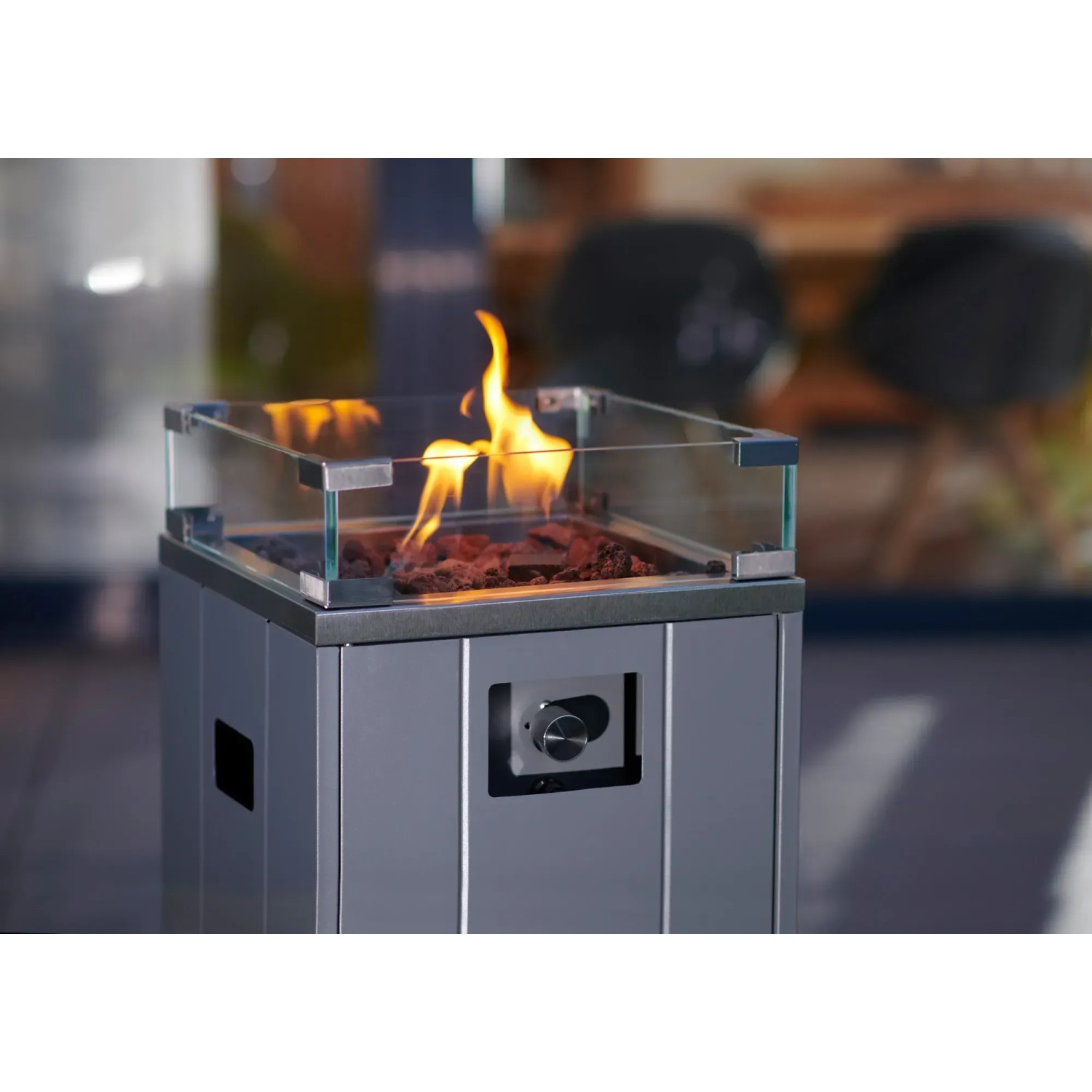 Grauer Buschbeck Terrassenheizer Malta mit Glasumrandung und Lavasteinen. Flammen sichtbar.