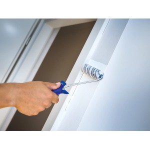 Hand streicht weiße Wand mit LUX Dispersionswalze 10 cm. Farbwalze mit blauem Griff.