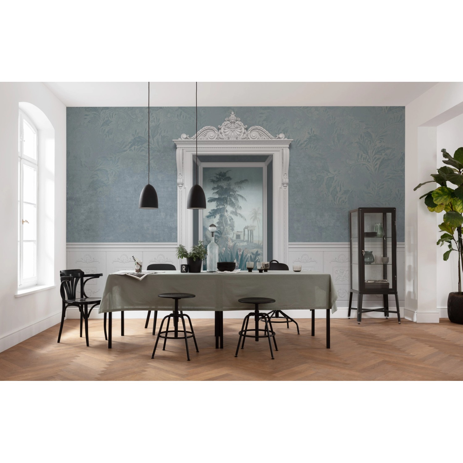 Komar Vlies Fototapete Niche 500x280 cm im Esszimmer mit blauem Wandbild und Stuckrahmen.