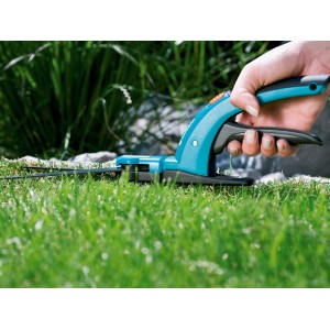 Gardena Comfort Grasschere in Aktion: Hand schneidet Rasenkante präzise. Gartenschere mit blau-schwarzem Griff.
