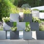 Scheurich C-Cube Pflanzgefäße in Stony Black, quadratisch gestapelt im Garten.