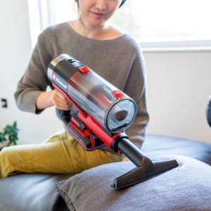 Frau saugt Kissen mit Einhell Akku-Stielstaubsauger und Zubehör-Set.